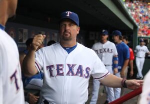 texas baseball player in dugout holding up fist looking at other player