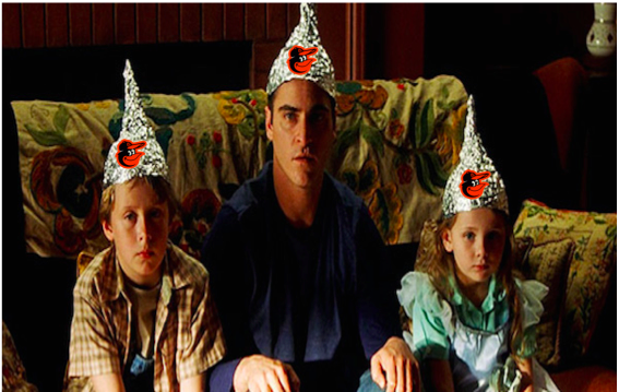 movie scene with three people on couch wearing foil hats with orioles logo