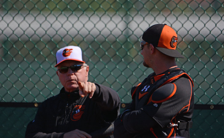Buck Showalter and Caleb Joseph in front of a fence.
