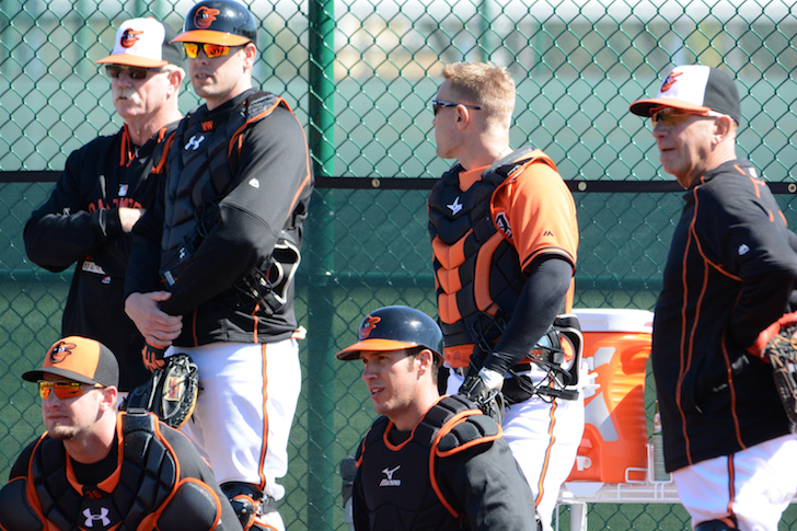 orioles players sitting around fence watching something