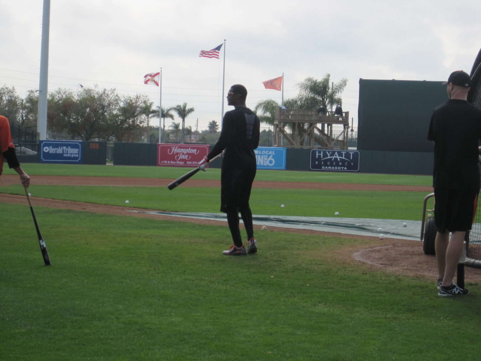 three men standing around baseball field with bats