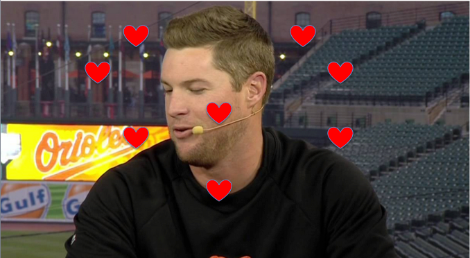 guy speaking in front of orioles stadium with hearts around his face