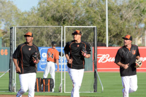 three orioles players running with gloves on field