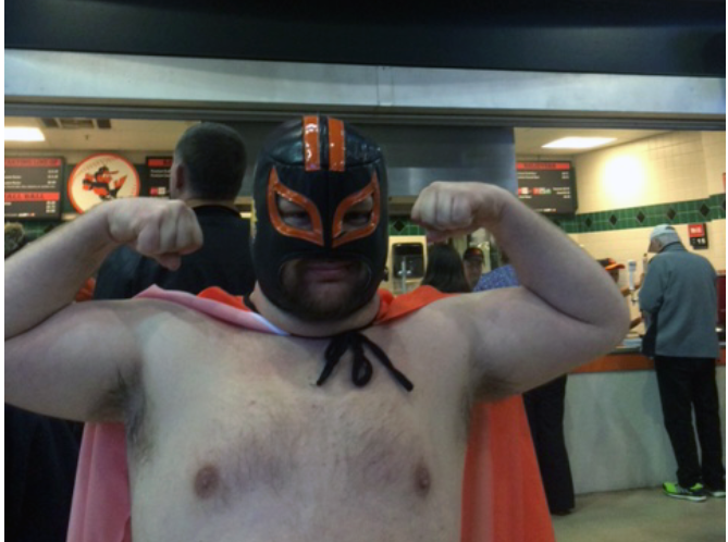 man with mask on flexing arms at concession stand
