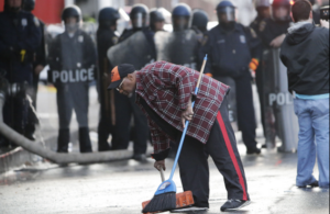 man sweeping street with police force behind him
