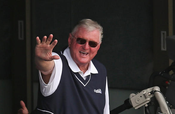 man wearing sunglasses waving from box seat