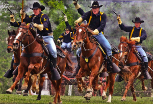 men on horses galloping holding up guns