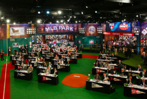 men sitting at draft tables in large open room decorated with sports stuff