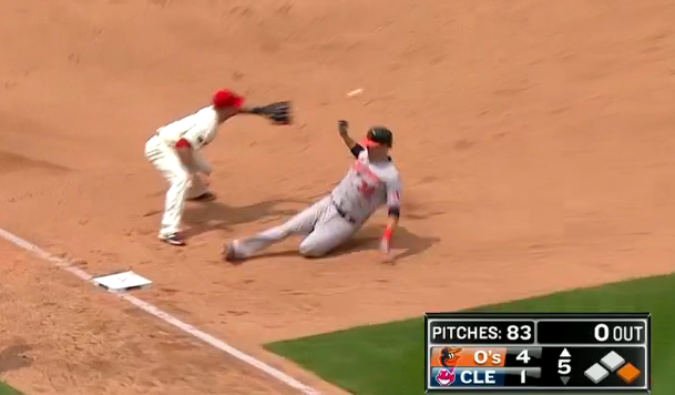 orioles player sliding into base with cleveland player about to catch ball