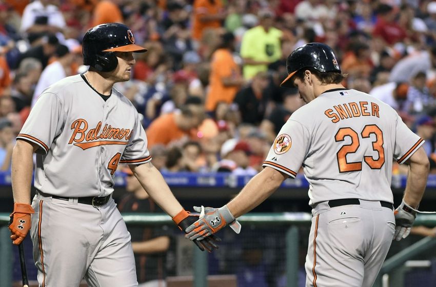 two Orioles team players smacking hands with crowd in background