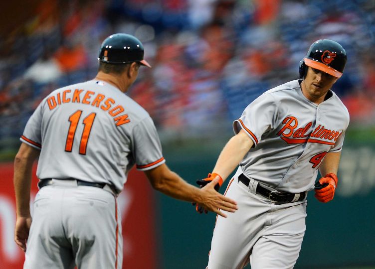 two orioles players slapping hands as one runs by the other