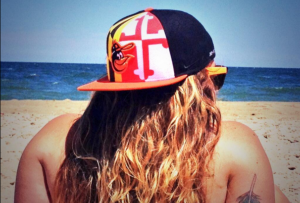 Amy sits with her MD flag O's hat on the beach.