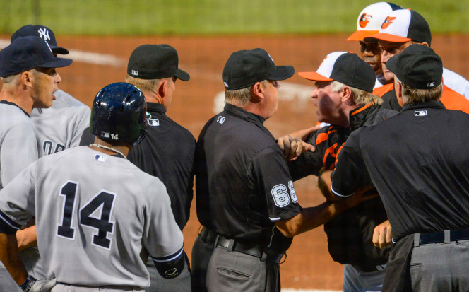 Buck Showalter and Joe Girardi yell at each other, separted by umpires.