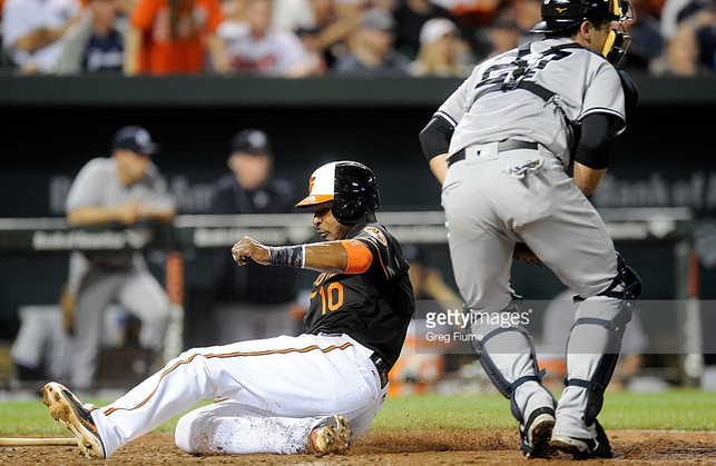 Adam Jones of the Orioles slides into home plate as the Yankees catcher takes the throw.