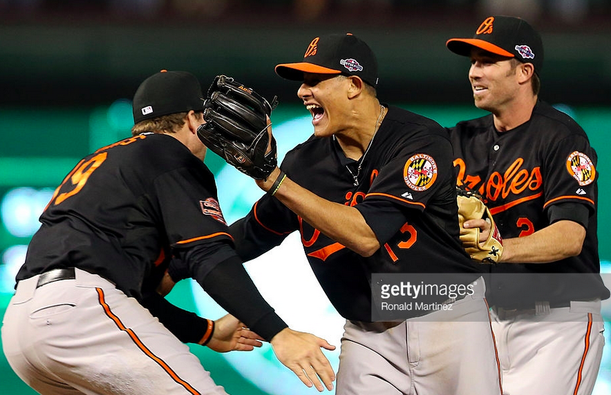 Three Orioles players celebrate on the field.