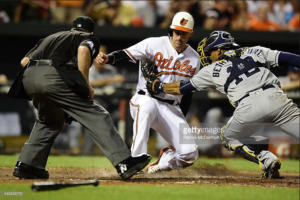 Ryan Flaherty slides into home as the Padres catcher applies the tag and the umpire watches.