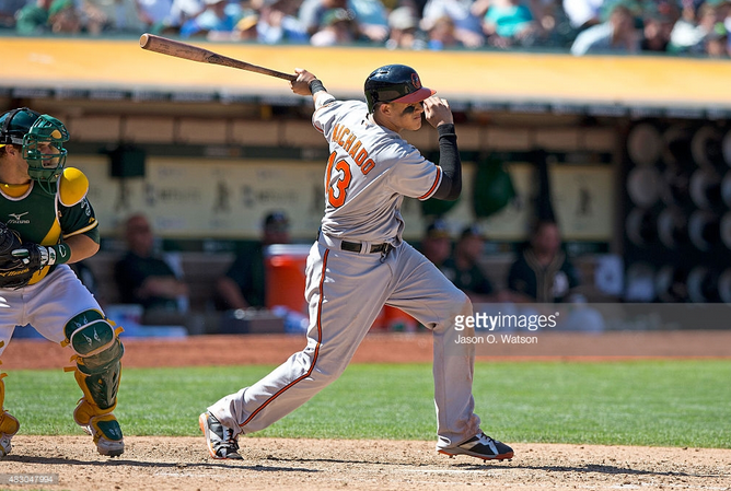 Manny Machado swings while the A's catcher stands behind him.
