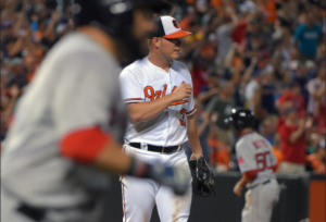 baseball players trot around the bases as the pitcher watches.