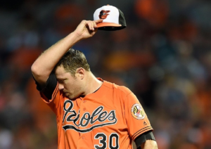 Chris Tillman, Orioles pitcher, wipes his brow with his arm.