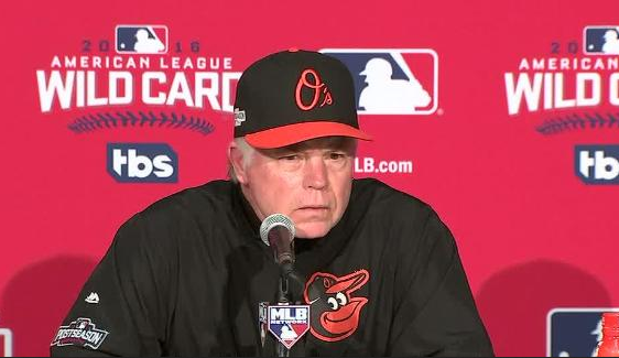 Buck Showalter sits at the press meeting desk at the wild card game.