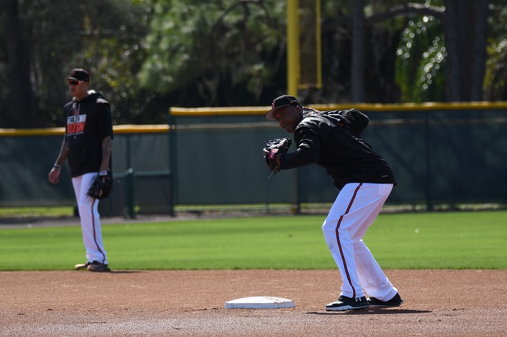 Jonathan Schoop prepares to throw to first as Manny Machado watches.