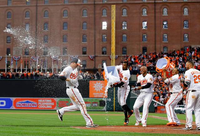 Mark Trumbo crosses home plate as his teammates douse him in water to celebrate.
