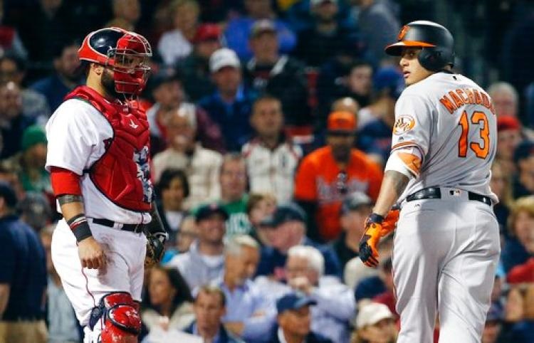 Manny Machado stares back at the Red Sox dugout after hitting a home run as catcher Sandy Leon watches.