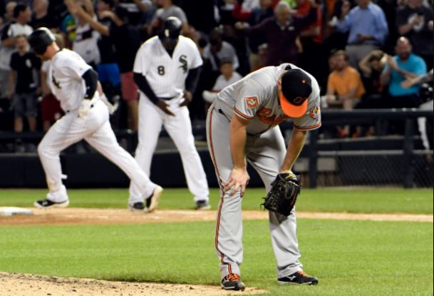Orioles pitcher Alec Asher puts his head down and hands on his knees as a White Sox player rounds first.
