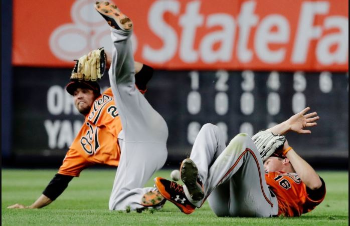Baltimore Orioles J.J. Hardy and Trey Mancini fall down trying to make a catch.