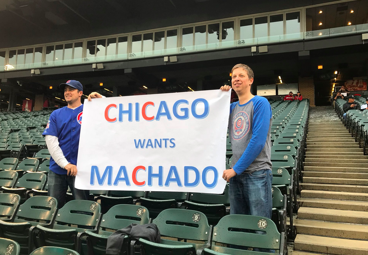 Cubs fans with a sign saying they want Manny Machado.