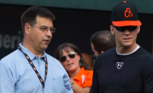 Dan Duquette and Brady Anderson stand near the Orioles dugout.