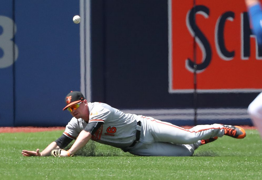 Trey Mancini of the Orioles dives as the baseball bounces by.